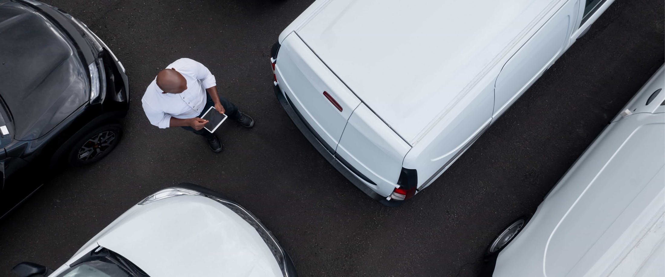 aerial view of A man checking tablet near vehicles