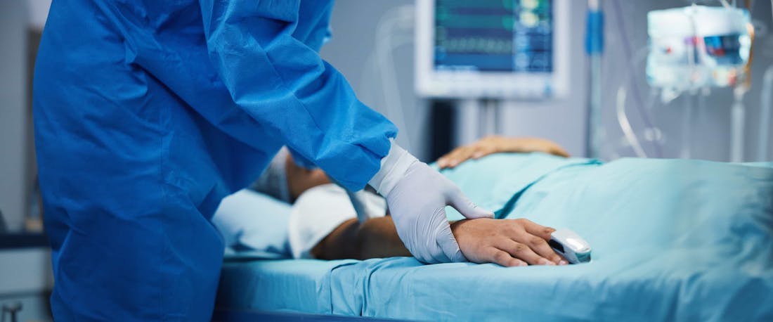 A doctor checking on an injured person in a hospital bed