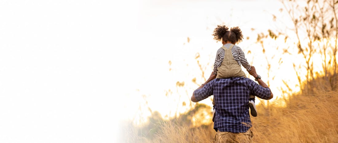 Man carrying a little girl on his shoulders