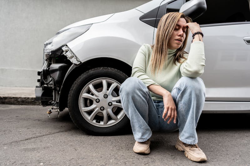 Woman sitting by a crashed car