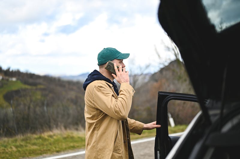A man talking on phone outside of car