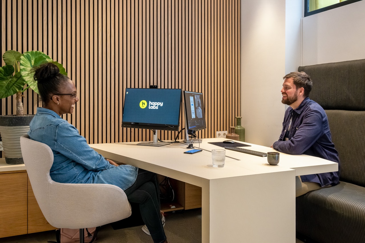 Two people sitting at a desk, talking