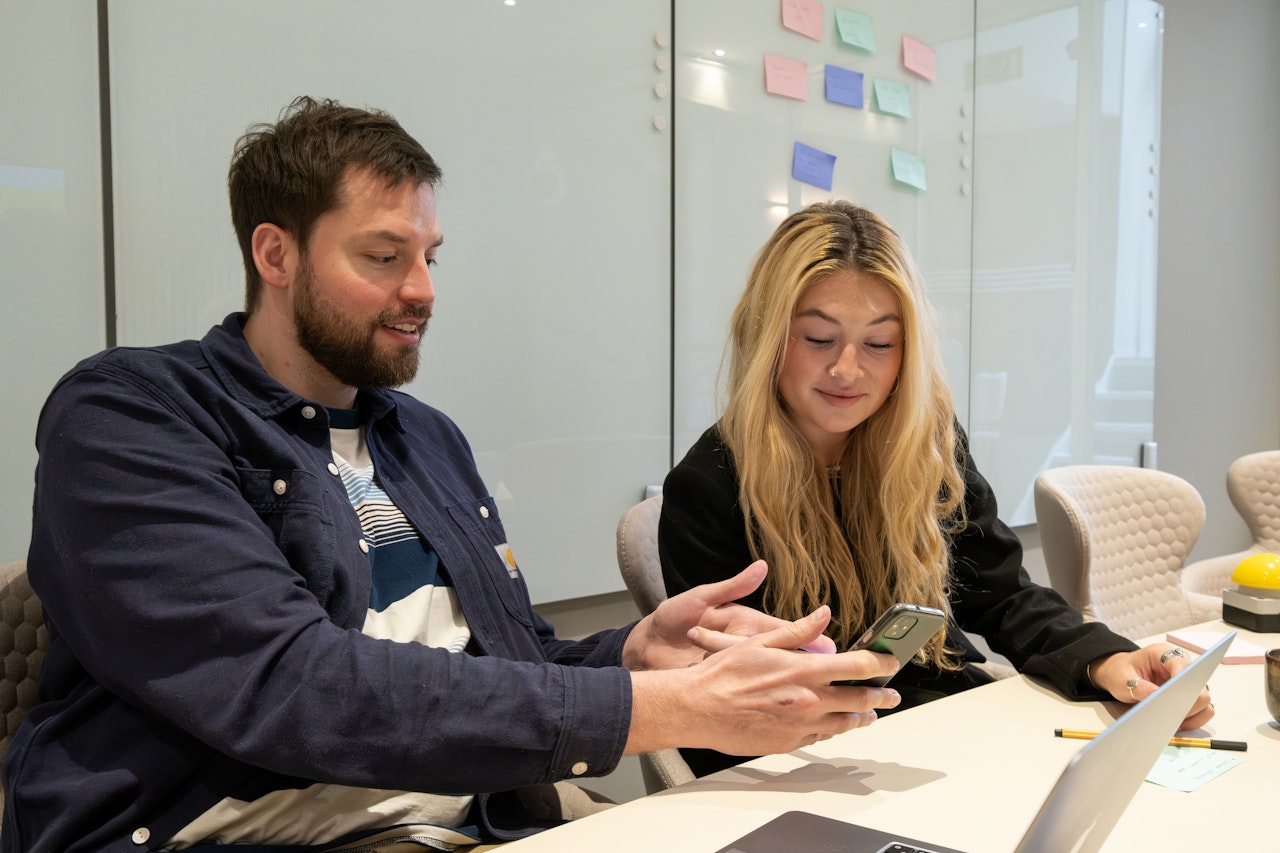 Two people sitting at a desk, talking