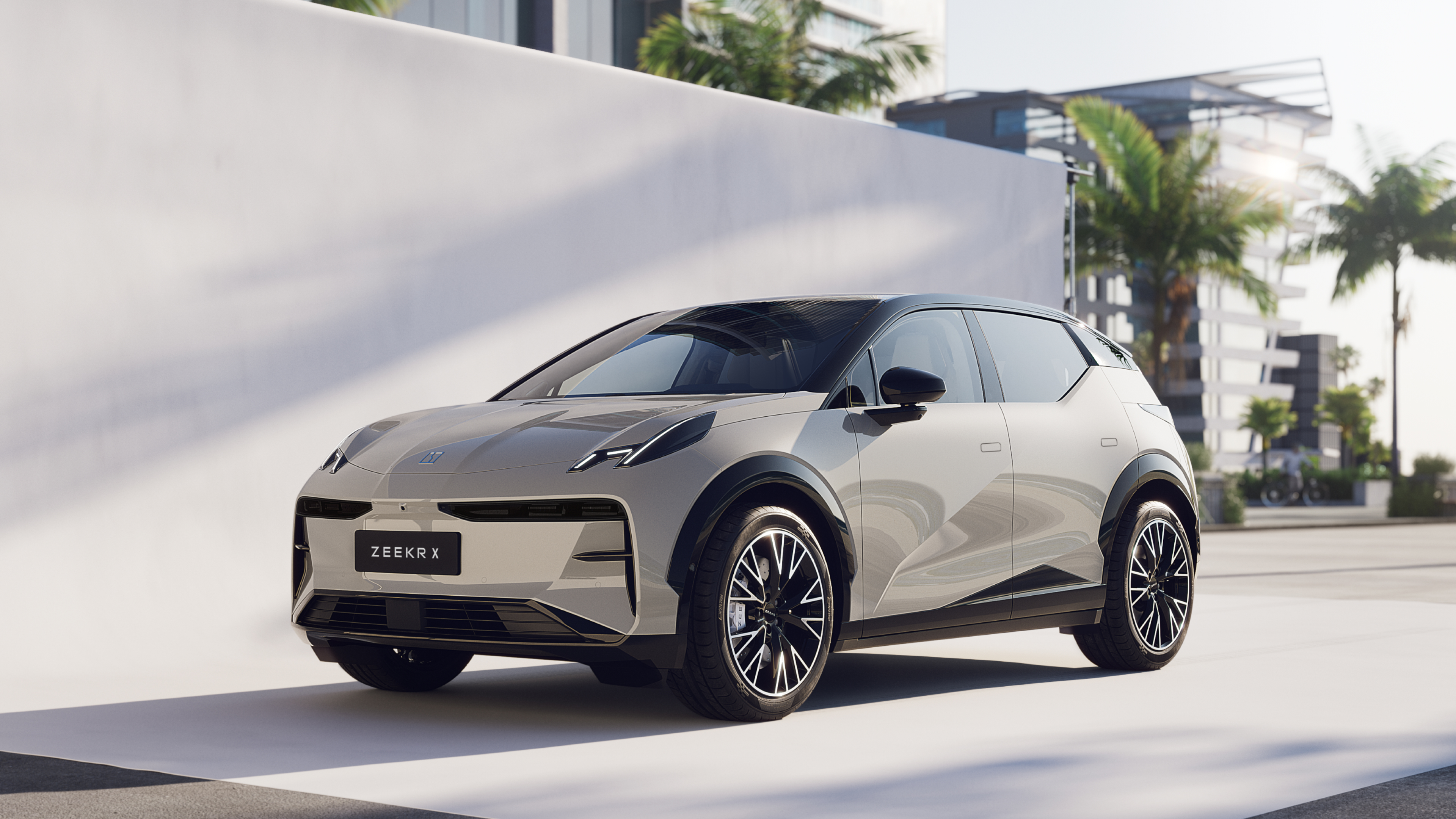 A Zeekr X electric SUV in Palace Beige, featuring a sleek aerodynamic design, black roof accents, and parked in a modern urban setting.