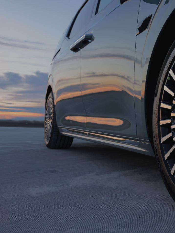 Close-up of the Zeekr 009’s 20-inch Starlight aero-style alloy wheels with MICHELIN Pilot Sport EV tyres, set against a sunset backdrop, highlighting the premium design and electric performance.