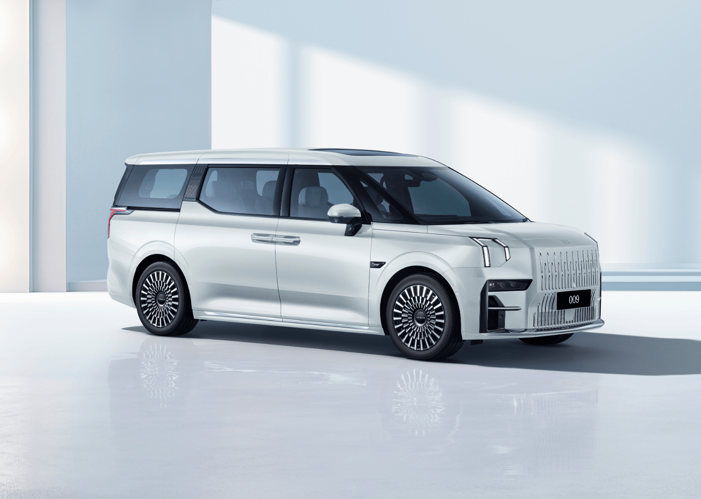 Side view of the Zeekr 009 electric MPV in Crystal White, featuring a bold grille, aerodynamic design, and premium alloy wheels.