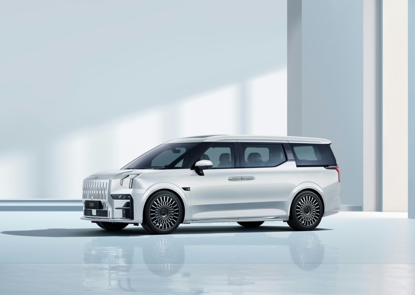Side view of the Zeekr 009 luxury electric MPV in Crystal White, highlighting its sleek design, bold grille, and premium aero wheels.