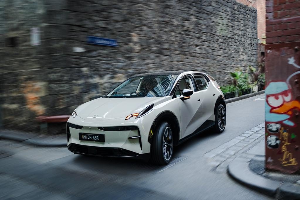 Zeekr X luxury electric SUV in Palace Beige exiting a laneway in Melbourne with graffiti on the wall.