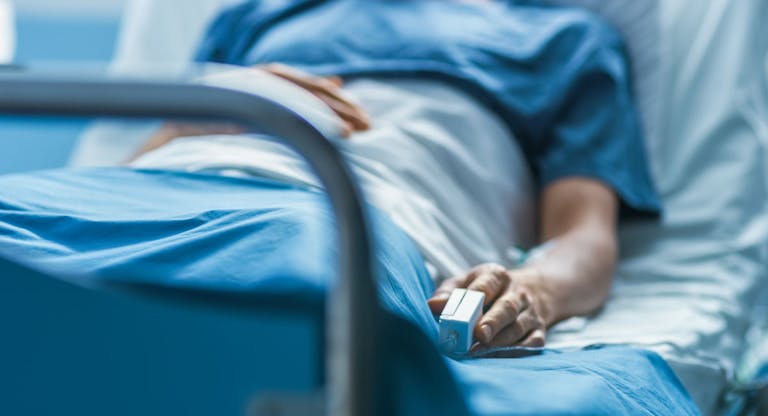 In the Hospital Sick Male Patient Sleeps on the Bed. Heart Rate Monitor Equipment is on His Finger.