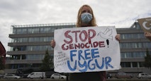 A woman holds a sign stating stop genocide. Organ harvesting, free uyghur. Uyghur, Uighur, Muslims, China, forced genocide.