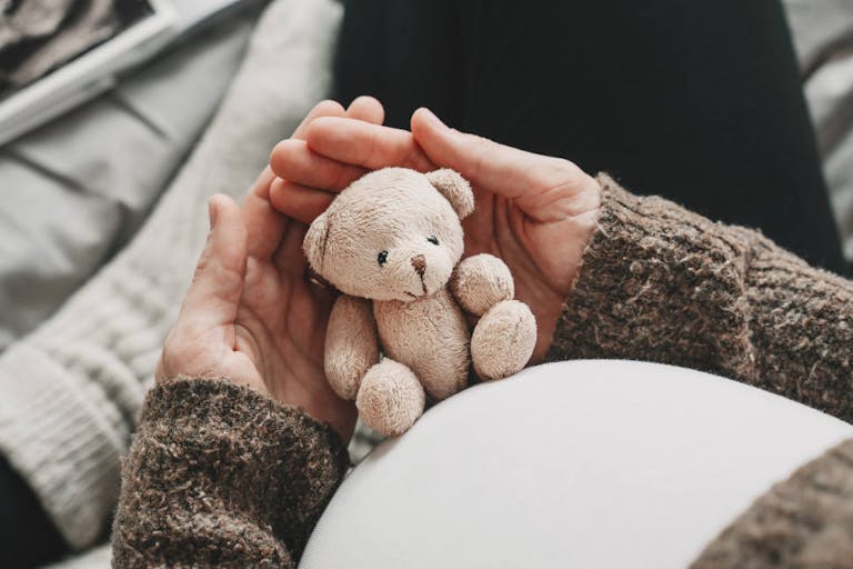 Woman pregnant belly with little teddy toy bear. Concept image with symbol of many meanings for expectant mother during pregnancy and her unborn baby.
