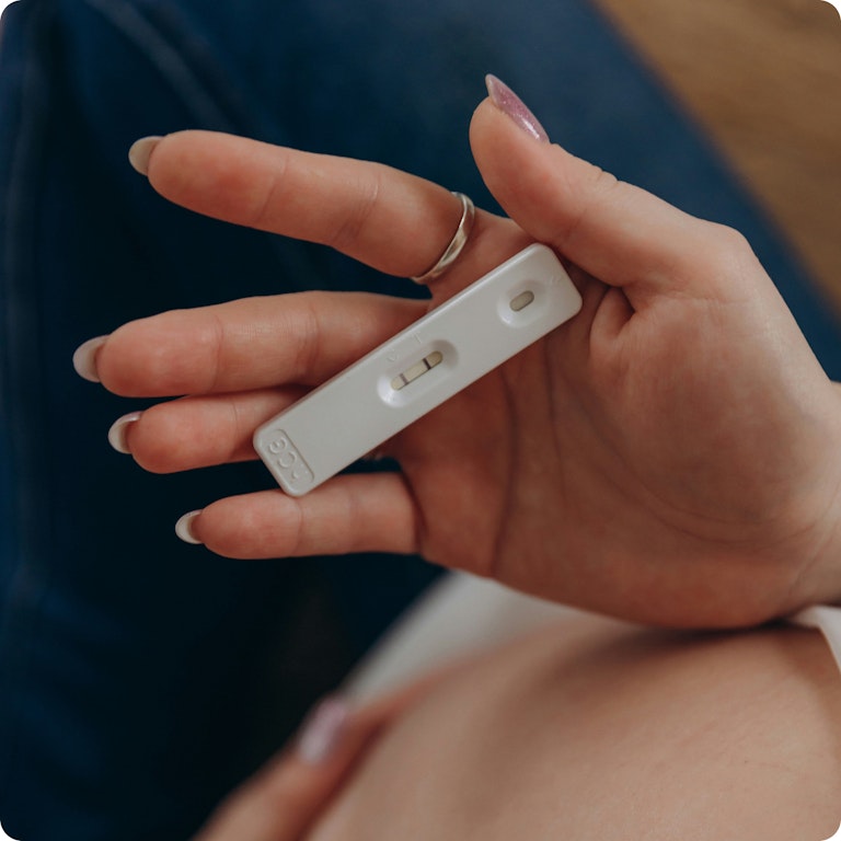 A woman's hand holding a positive pregnancy test