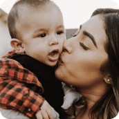 A mom kissing her baby boy on the cheek