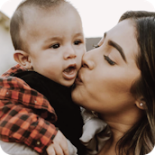 A mom kissing her baby boy on the cheek