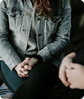 Woman in jean jacket with clasped hands in lap