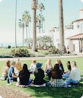 A group of woman sitting in a circle on the grass