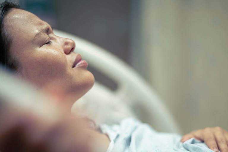 A sick woman patient in bed at the hospital suffering from pain. Contractions and childbirth.