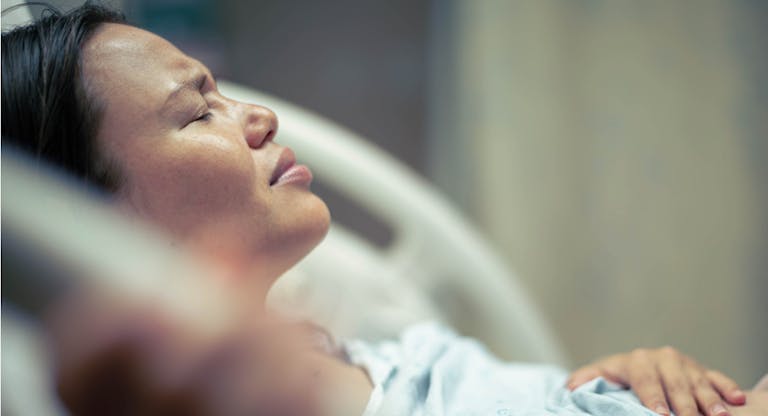 A sick woman patient in bed at the hospital suffering from pain. Contractions and childbirth.