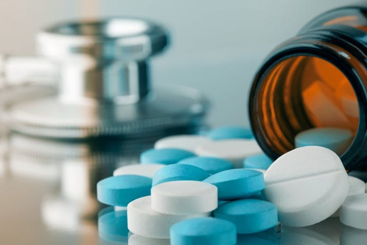 Blue and white pills are spilled near a stethoscope. assisted suicide, assisted death, euthanasia, euthanized
