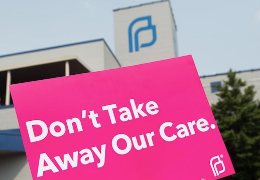 A hot pink protest sign outside of planned parenthood headquarters