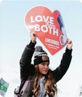 Teenage girl holding up a heart shaped sign