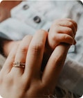 A tiny baby hand wrapped around a women's finger