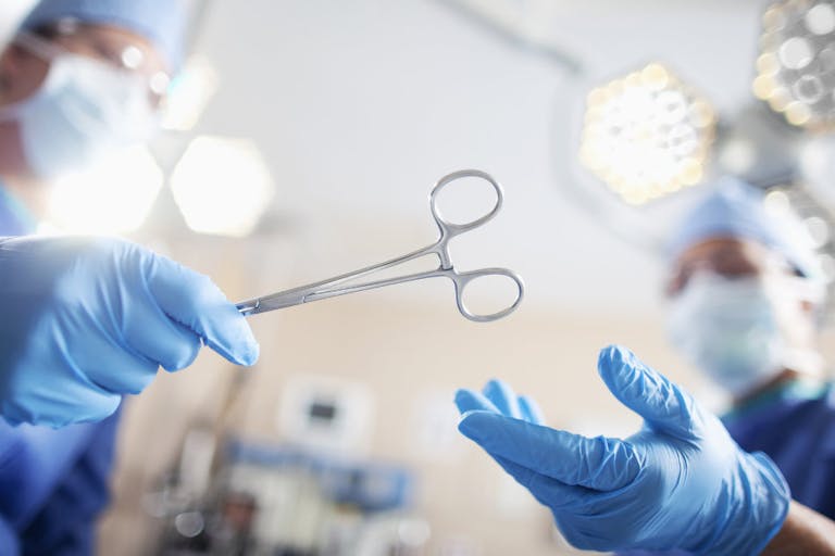 Low angle view of hands of doctor surgeon nurse passing medical equipment tool in surgery operating room hospital