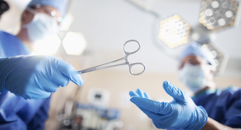 Low angle view of hands of doctor surgeon nurse passing medical equipment tool in surgery operating room hospital
