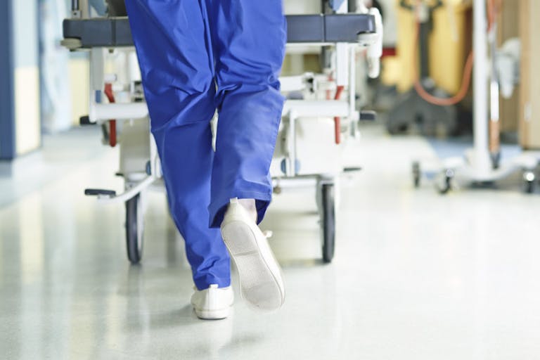 Legs of medic running with gurney along hospital corridor