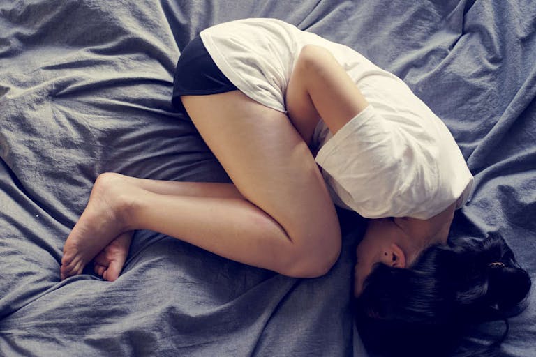 asian female feel hurt and pain on period on the bed