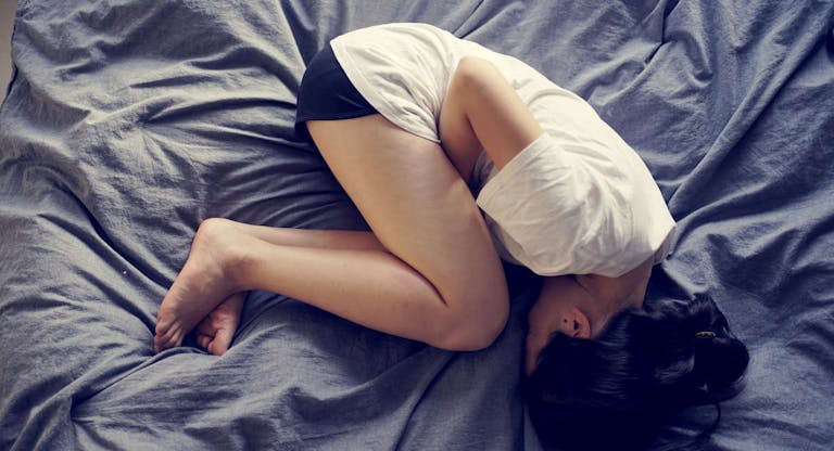 asian female feel hurt and pain on period on the bed