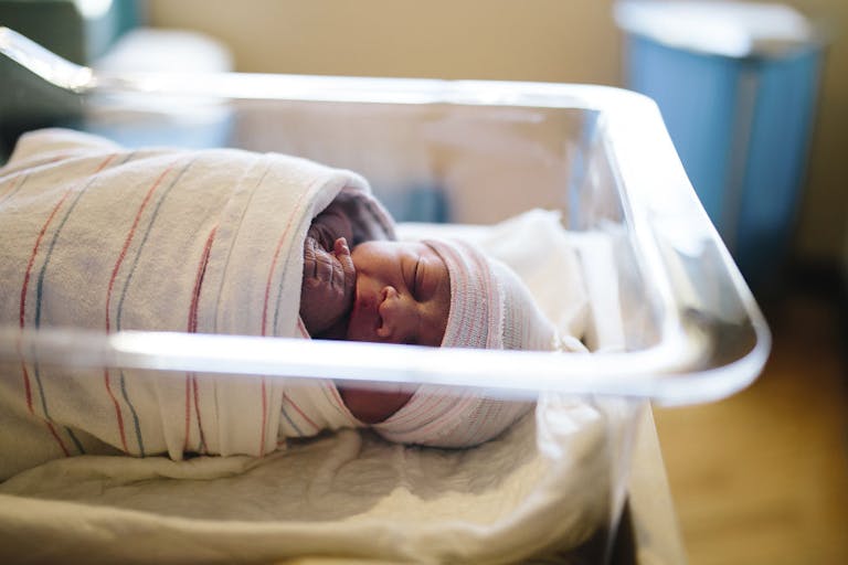 High angle view of cute newborn baby boy sleeping in hospital bassinet New CDC data shows U.S. birth rate remains near record low featured image