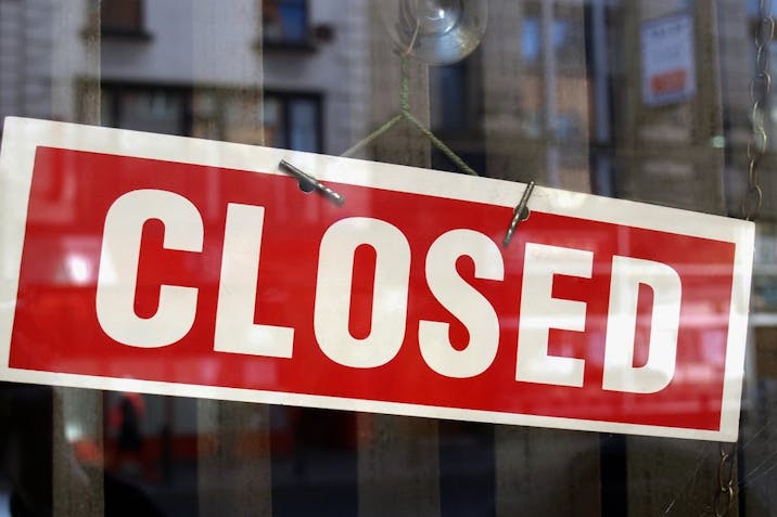 Photo: Getty Images image of red and white closed sign behind glass window