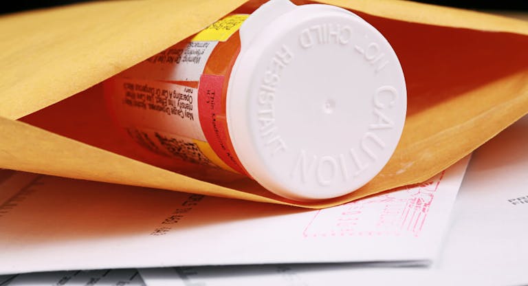 A close-up of a pill bottle in an envelope