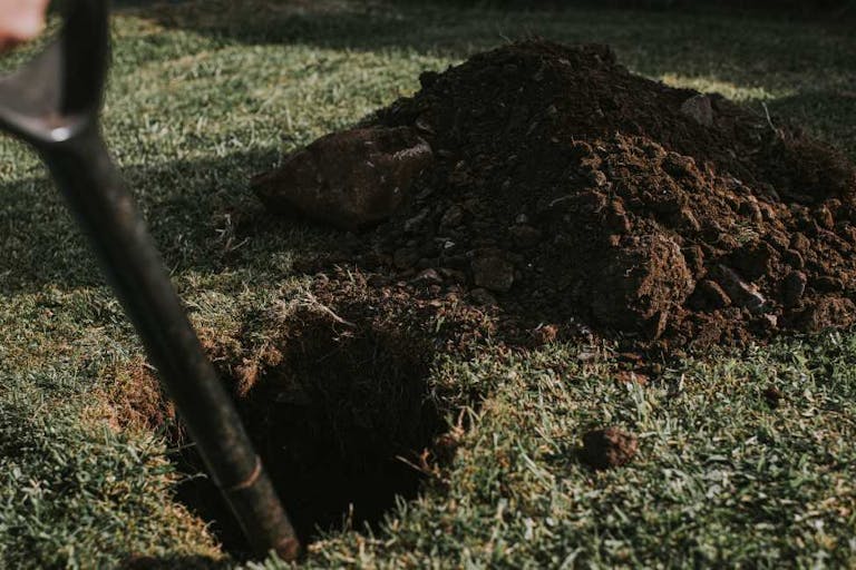 Person digging a hole in a garden with a spade