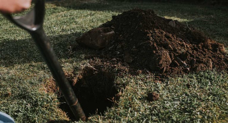 Person digging a hole in a garden with a spade