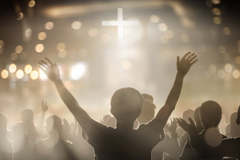 Christians raising their hands in praise and worship at a night music concert Appeals court: Washington church must include abortion in insurance coverage featured image