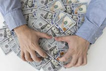 Man’s hands and a lot of dollar bills on a white table. Bribes, corrupt, cash. US dollars in male hands. The concept of profit, wages.