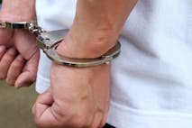 gettyimages-1179534529-handcuffs Close up of handcuffed hands held against a white shirt