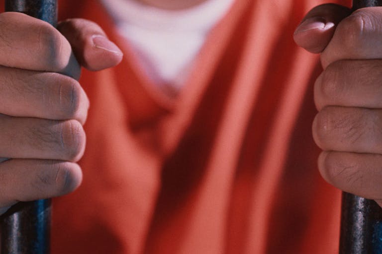 Prisoner Holding Bars of Cell Australian criminal allowed to impregnate his girlfriend from prison using IVF featured image