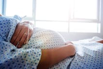 Photo: Sergey Novikov/Ripicts.com via Getty Images Close-up of a pregnant woman's belly in the hospital bed with catheter in hand
