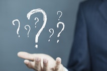 Businessman on blurred background holding hand drawn question marks