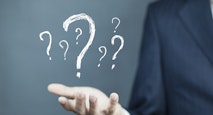 Businessman on blurred background holding hand drawn question marks