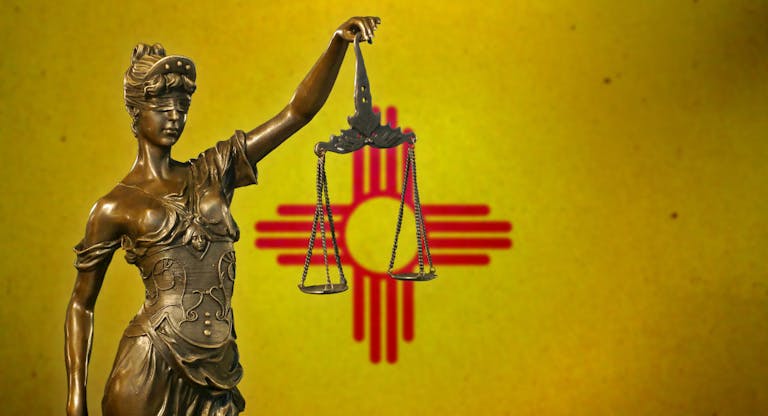Lady Justice before a flag of New Mexico