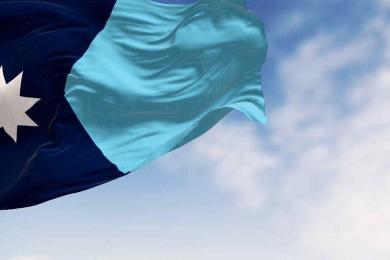 Close-up of Minnesota new state flag waving with the american flag on a clear day Following legislative changes, Minnesota saw a big jump in abortions in 2023 featured image