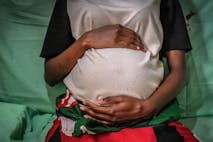 Photo: SOPA Images/Getty Images Kenyan woman cradles her pregnant belly