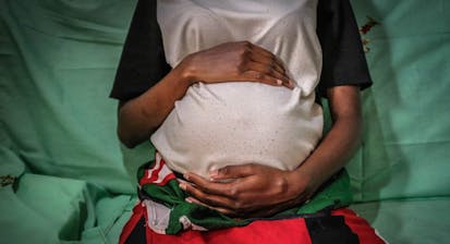 Kenyan woman cradles her pregnant belly