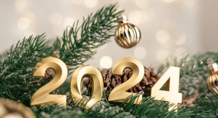 Golden numbers 2024 on the background of spruce, Christmas balls and bokeh