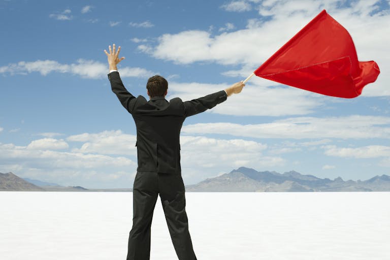 Businessman Waving Red Flag on Salt Flats.