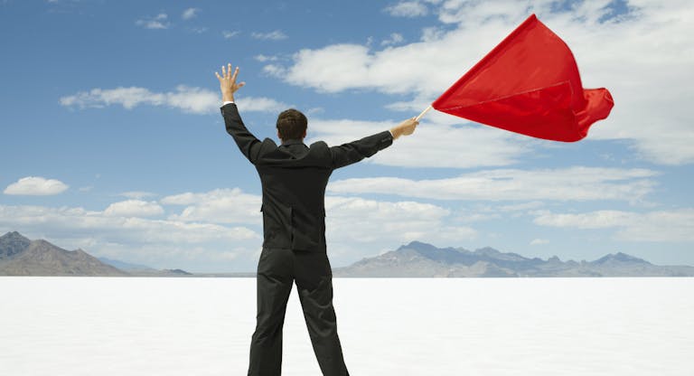 Businessman Waving Red Flag on Salt Flats.